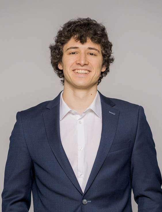 A professional photo of Noah Berner wearing a suit and smiling into the camera.